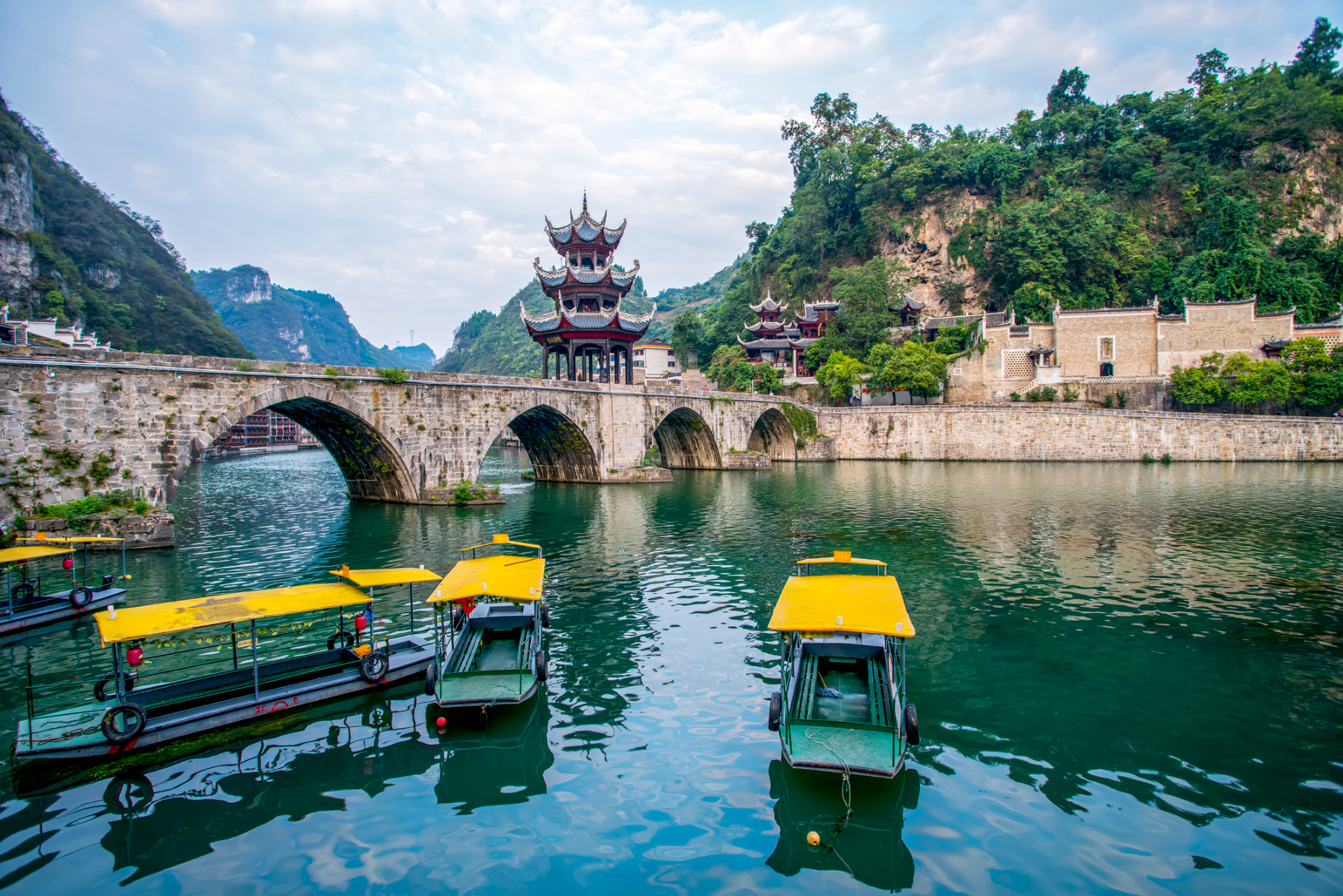 Pleasure boats below the pagoda-topped ancient bridge in Zhenyuan