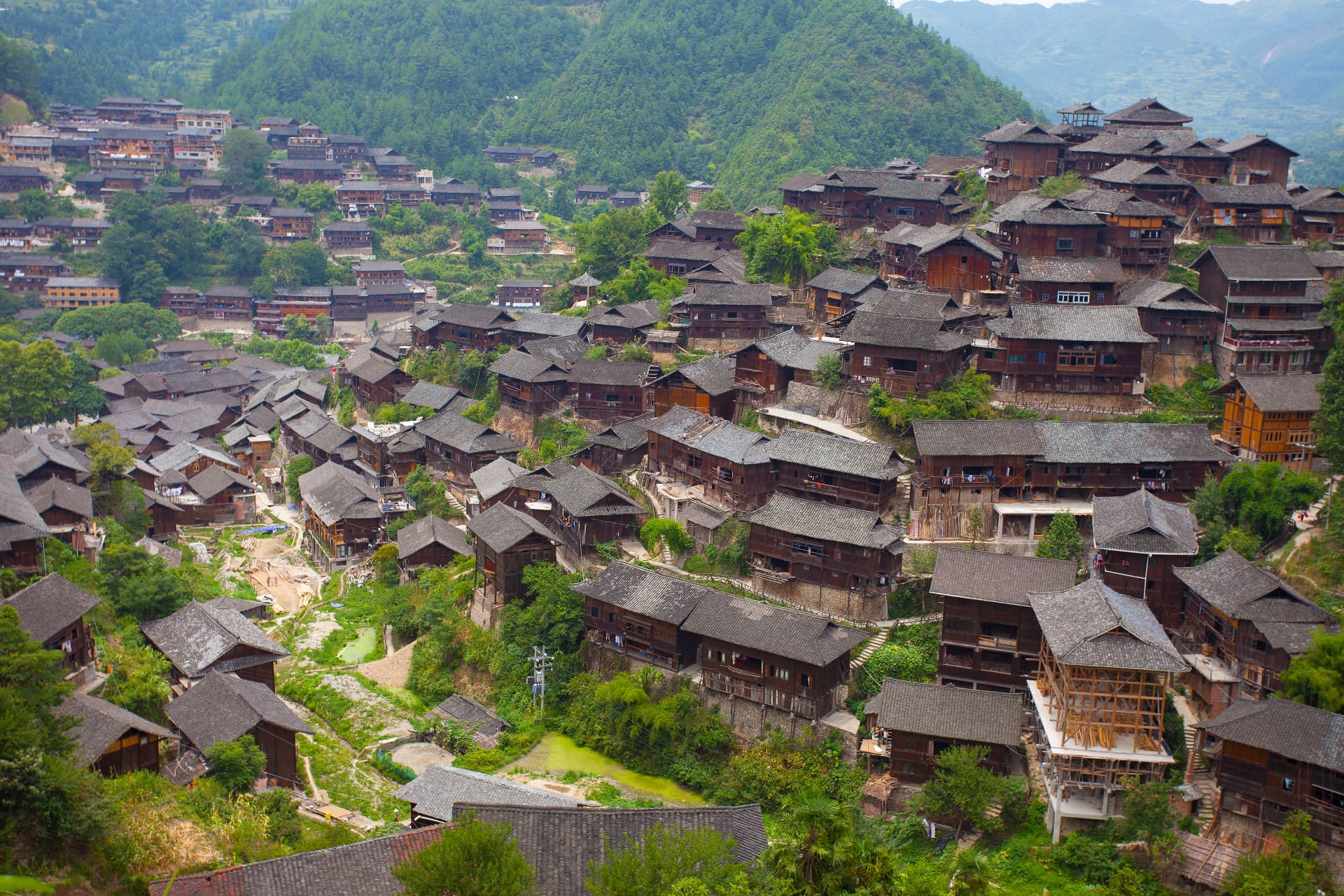 Stilted wooden houses climbing the hillside at Xijiang Miao village