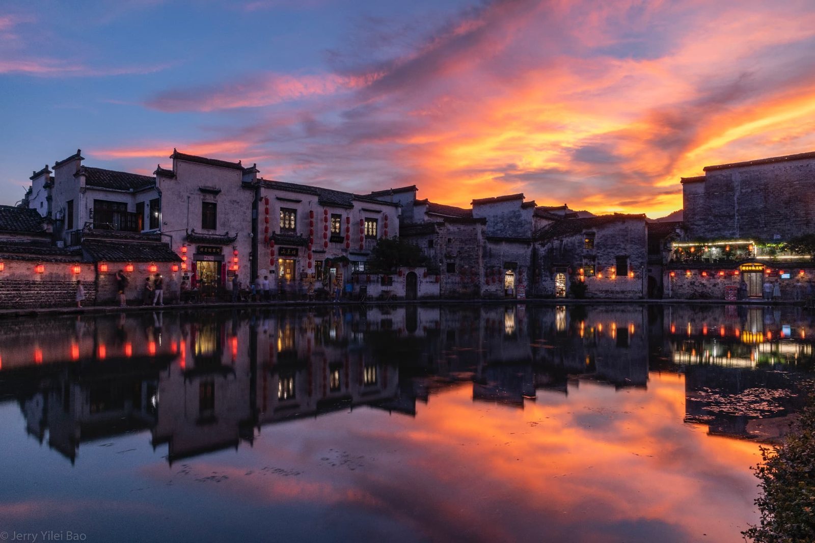Fiery sunset over Hongcun's lantern-lit houses and still pond