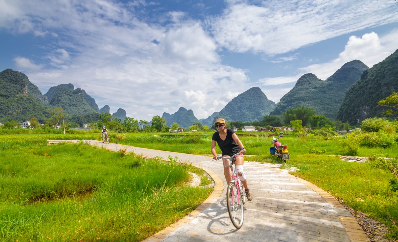 Cyclist on a countryside path near Yangshuo with karst peaks behind