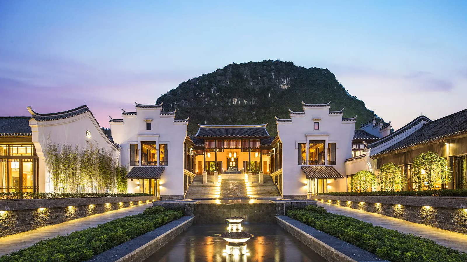 Banyan Tree Yangshuo entrance courtyard lit at dusk beneath a karst peak
