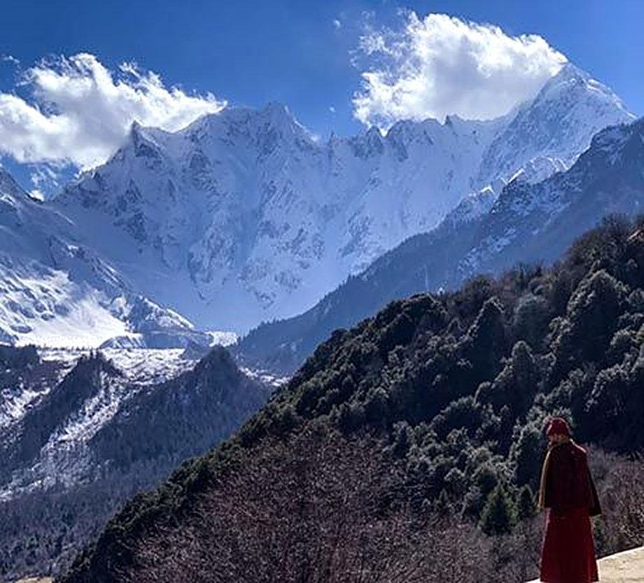 Monk overlooking snow-capped peaks near Bome