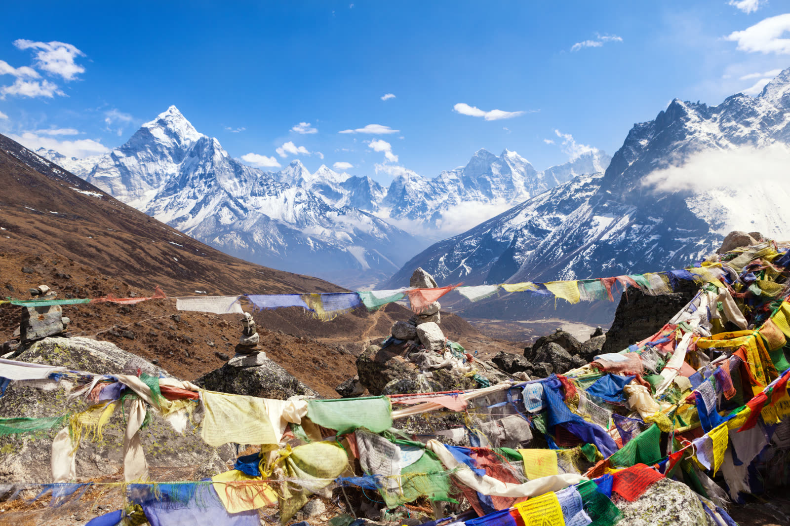 Prayer flags strung across a high pass with snow-capped Himalayan peaks beyond